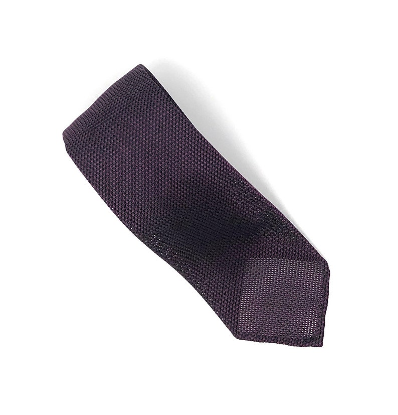 Puede incluir: Una corbata de punto de color morado oscuro con un patr&oacute;n de textura fina.