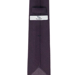 Puede incluir: Una corbata de punto de color morado oscuro con una etiqueta blanca que dice "WILMOK ROME".