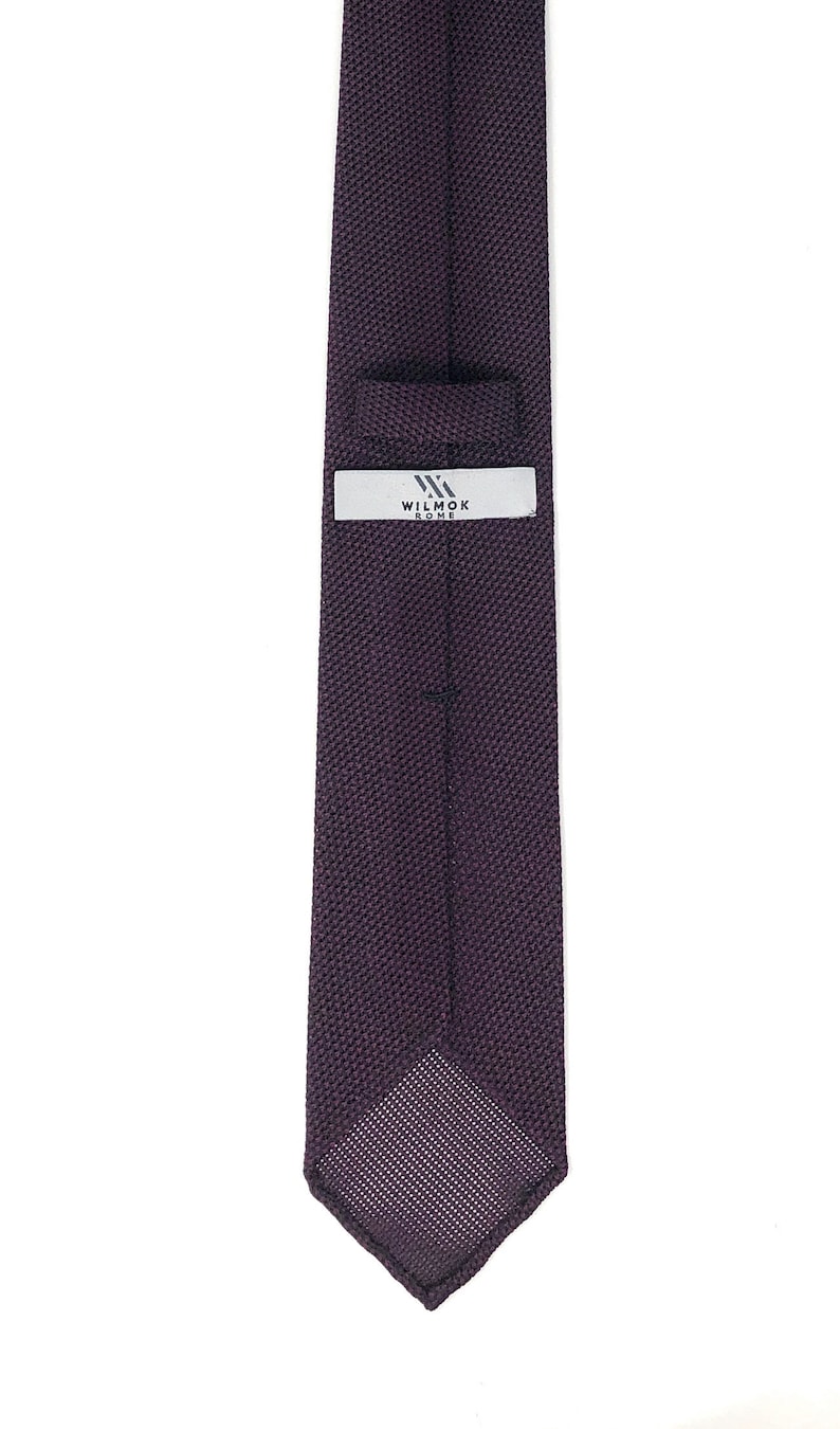 Puede incluir: Una corbata de punto de color morado oscuro con una etiqueta blanca que dice "WILMOK ROME".