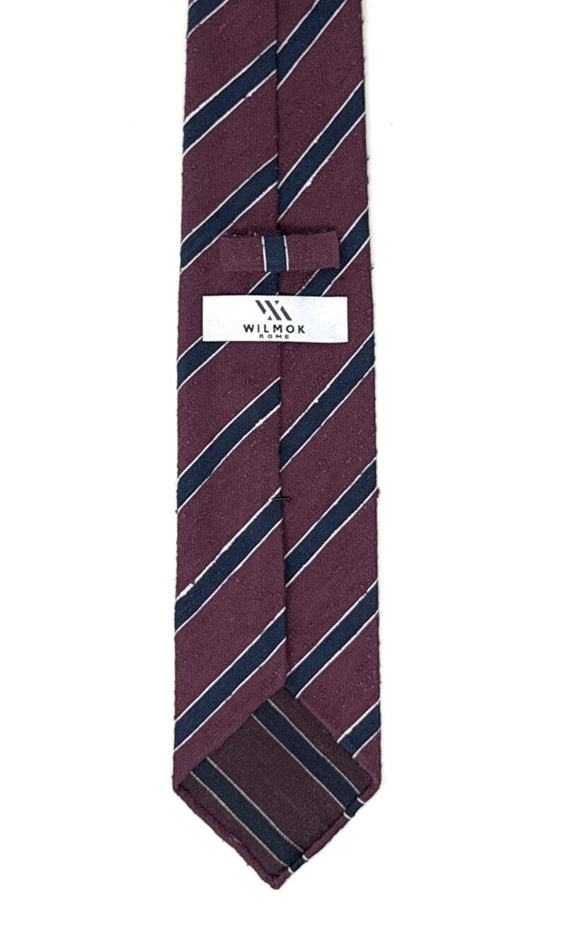 May include: A burgundy and navy striped tie with a white label that reads "WILMOK ROME".