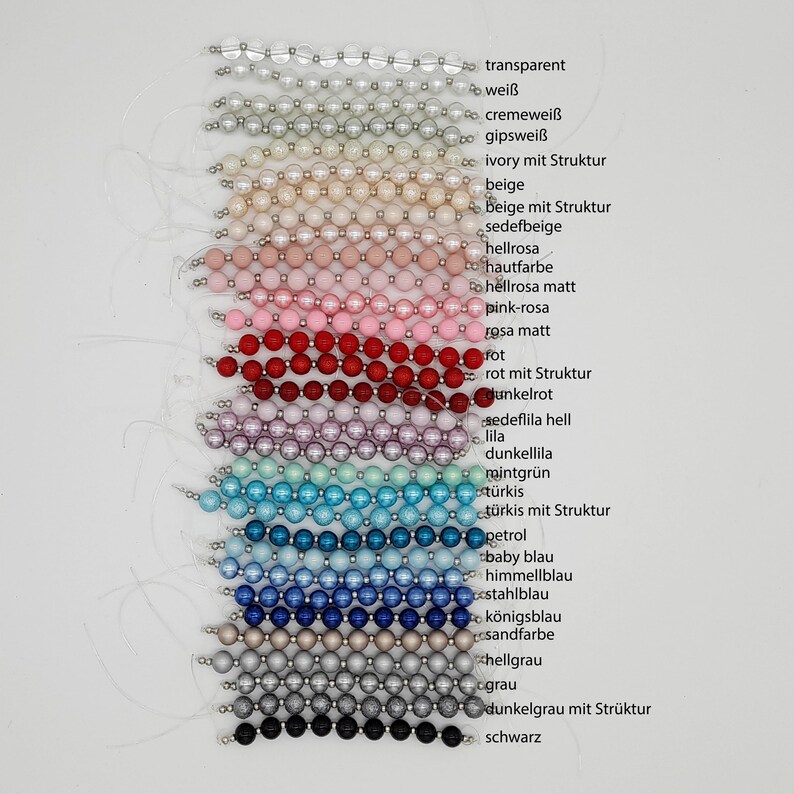 Puede incluir: Una carta de colores de cuentas con diferentes colores y texturas. Las cuentas est&aacute;n dispuestas en filas, con cada fila representando un color diferente. Los colores incluyen transparente, blanco, crema, marfil, beige, rosa, rojo, morado, verde, azul, gris y negro. Algunas de las cuentas tienen una superficie texturizada, mientras que otras son lisas.