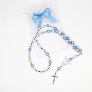 Könnte beinhalten: Blaue und weiße Perlenkette mit einem silbernen Kreuz und einem Engelsanhänger. Die Perlen sind mit dem Namen "CHRISTIAN PAUL" personalisiert.
