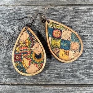 May include: A pair of teardrop-shaped wooden earrings with a colourful patchwork design. The earrings are made of cork and have a natural wood finish.