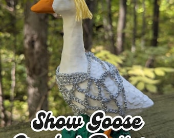 May include: A white goose figurine with an orange beak and yellow hair, adorned with a silver crocheted collar and headpiece. The base is green. Text on the image reads "digital download PDF file" and "Show Goose Crochet Pattern".