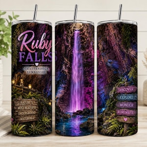 May include: A cylindrical metal tumbler with a straw featuring a wrap-around print of Ruby Falls in Chattanooga, Tennessee. The design includes a purple-lit underground waterfall, lush greenery, and wooden signs with text including Nature's Most Beautiful Underground Waterfall, Discover, Explore, Wonder, and Remember.