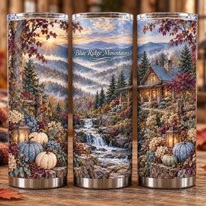 May include: A cylindrical metal tumbler featuring a wrap-around autumn landscape print of the Blue Ridge Mountains, a rustic cabin, a cascading waterfall, and pumpkins. The text Blue Ridge Mountains is printed in white script on the center.
