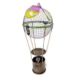 May include: A decorative metal hot air balloon with a green, yellow, and pink wire mesh basket and a gold base. The balloon is suspended from a gold metal stand.