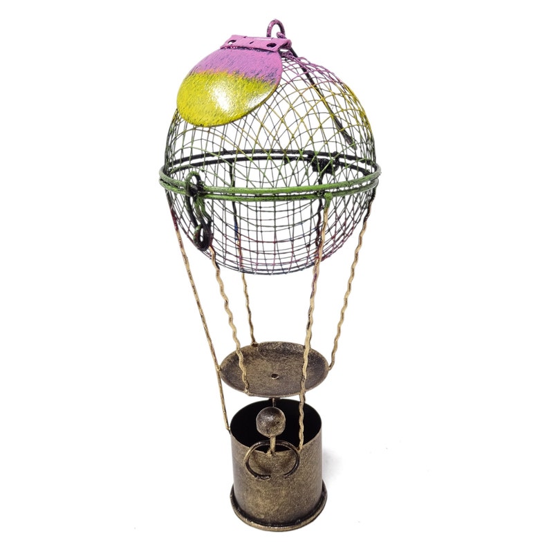 May include: A decorative metal hot air balloon with a green, yellow, and pink wire mesh basket and a gold base. The balloon is suspended from a gold metal stand.