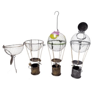 May include: Four decorative metal hot air balloon ornaments with wire baskets. The balloons are in various colors, including green, yellow, pink, and black. The baskets are made of wire and have a rustic look.