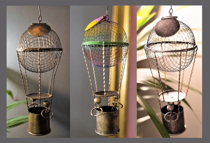 May include: Three decorative metal hot air balloons with wire mesh baskets and different colored tops. The balloons are hanging from the ceiling.