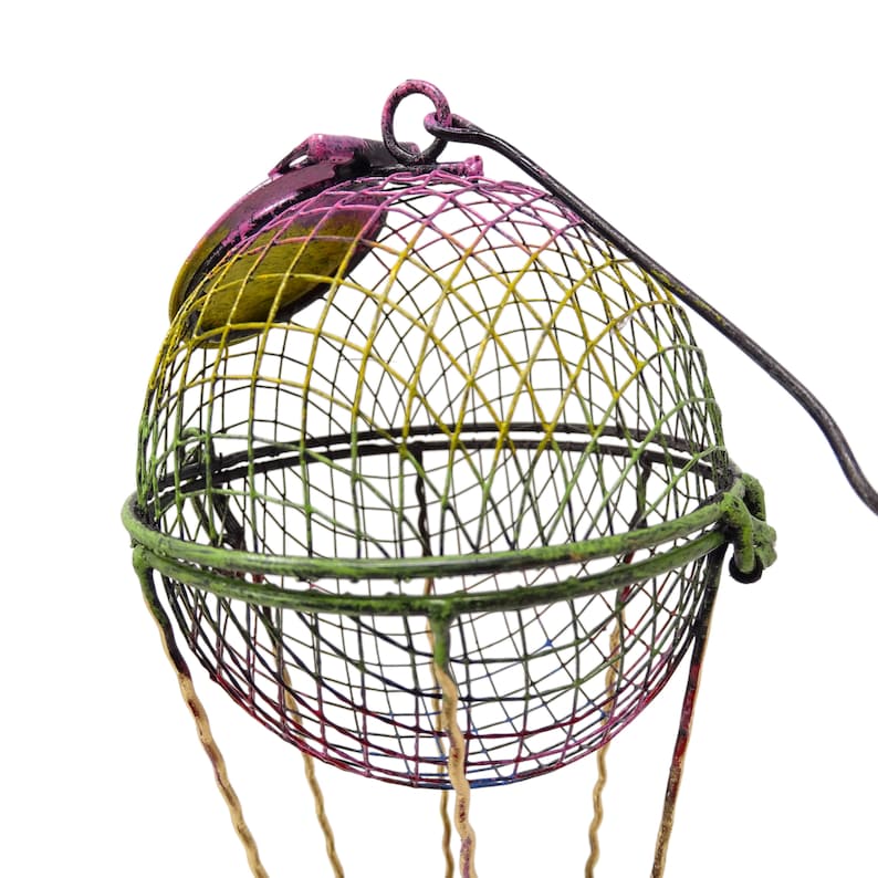 May include: A colorful metal hot air balloon with a wire mesh basket and a pink and yellow top. The balloon is decorated with yellow, green, and pink paint.