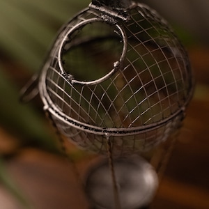May include: A silver metal hot air balloon candle holder with a wire mesh design. The balloon is open at the top and has a small candle inside.