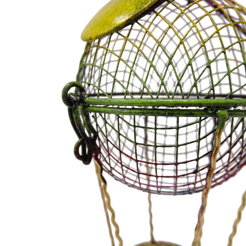 May include: A green, yellow, and red metal hot air balloon with a wire mesh basket. The balloon is made of wire and has a decorative design.