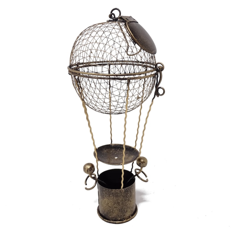 May include: A gold metal hot air balloon shaped decorative object with a wire mesh basket and a round top. The balloon has a small, round, metal lid on top.