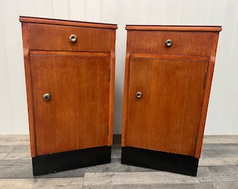 May include: Two wooden bedside tables with a single drawer and a cabinet door. Each table has a black base.