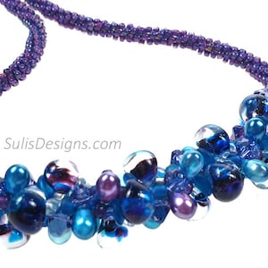 May include: A purple and blue beaded necklace with a cluster of glass beads in shades of blue and purple.