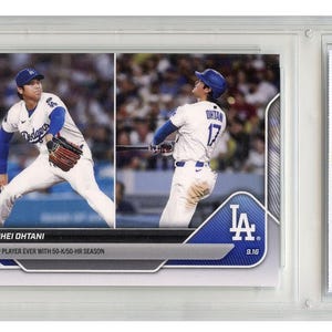May include: A baseball trading card featuring Shohei Ohtani of the Los Angeles Dodgers. The card shows two action shots of Ohtani in his Dodgers uniform. The card is encased in a protective holder and includes text that reads "2025 MLB Topps Now".