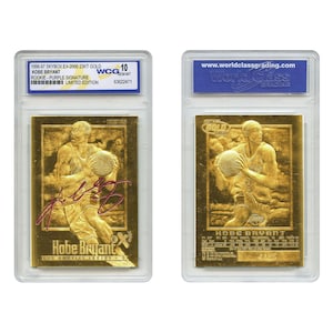 May include: Two gold-colored Kobe Bryant basketball cards in protective cases. The front card features a purple signature and the text "Kobe Bryant" and "Los Angeles Lakers." The back card has the text "GOLD" and "HOBE BRYANT."