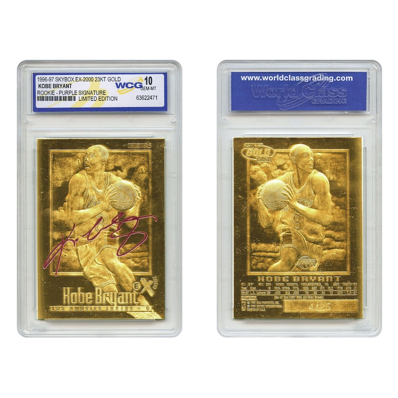 May include: Two gold-colored Kobe Bryant basketball cards in protective cases. The front card features a purple signature and the text "Kobe Bryant" and "Los Angeles Lakers." The back card has the text "GOLD" and "HOBE BRYANT."