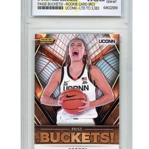 Puede incluir: Una tarjeta de novato Panini Instant NIL de Paige Bueckers, calificada WCG 10 GEM-MT. La tarjeta presenta a Bueckers con un uniforme de baloncesto de UConn sosteniendo un bal&oacute;n. La tarjeta dice "PAIGE BUCKETS!" y "UCONN".