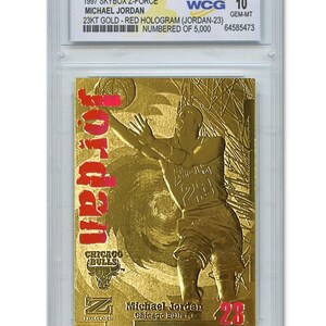May include: A gold-colored Michael Jordan trading card from the 1997 Skybox Z-Force series. The card features a red hologram of Jordan in action, with the Chicago Bulls logo and the number 23. The card is graded WCG 10.