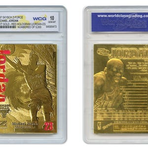 May include: Two gold-colored Michael Jordan basketball cards in protective cases. The front card features Jordan in action with the word "Jordan" in red. The back card shows a close-up of Jordan's face. Both cards are graded and numbered.