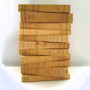Può includere: Una pila di libri d'epoca con copertine ingiallite e titoli in francese. I dorsi mostrano titoli come "Théâtre Choisi" e "Histoire Tragique". I libri sono disposti verticalmente, suggerendo una collezione di letteratura classica.