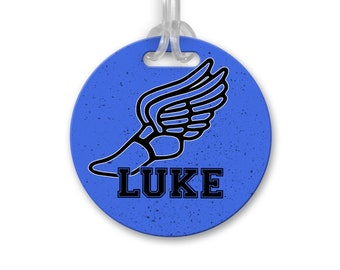 May include: Blue round luggage tag with a black winged shoe graphic and the name "LUKE" in black text.