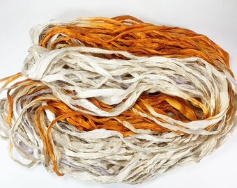Könnte beinhalten: Ein Bündel aus weißem und orangefarbenem Seidenband, perfekt zum Basteln und um Projekten einen Hauch von Eleganz zu verleihen.