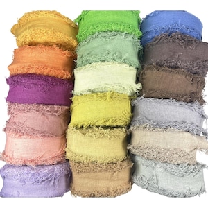 May include: A collection of fifteen fabric ribbon spools arranged in three columns, each featuring a frayed edge design. The ribbons come in a variety of colors including yellow, orange, purple, pink, lavender, green, lime, olive, blue, brown, gray, and beige.