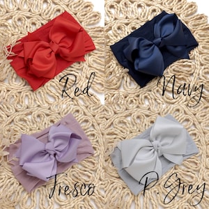 Peut inclure: Quatre bandeaux pour b&eacute;b&eacute;, rouge, marine, lavande et gris clair, chacun avec un grand n&oelig;ud. Les bandeaux sont pr&eacute;sent&eacute;s sur une surface beige tiss&eacute;e. Les couleurs sont &eacute;tiquet&eacute;es avec les mots "Red", "Navy", "Fresco" et "P. Grey".