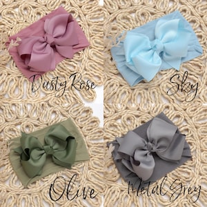 Peut inclure: Quatre bandeaux pour b&eacute;b&eacute; dans les couleurs Dusty Rose, Sky, Olive et Metal Grey. Chaque bandeau est orn&eacute; d'un grand n&oelig;ud sur un bandeau en tissu doux. Les noms des couleurs sont &eacute;crits en cursive.