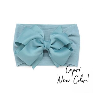 Peut inclure: Un bandeau pour b&eacute;b&eacute; bleu clair avec un grand n&oelig;ud. Le bandeau est en tissu doux et extensible, et le n&oelig;ud est en satin assorti. Le texte sur l'image indique "Capri New Color!"