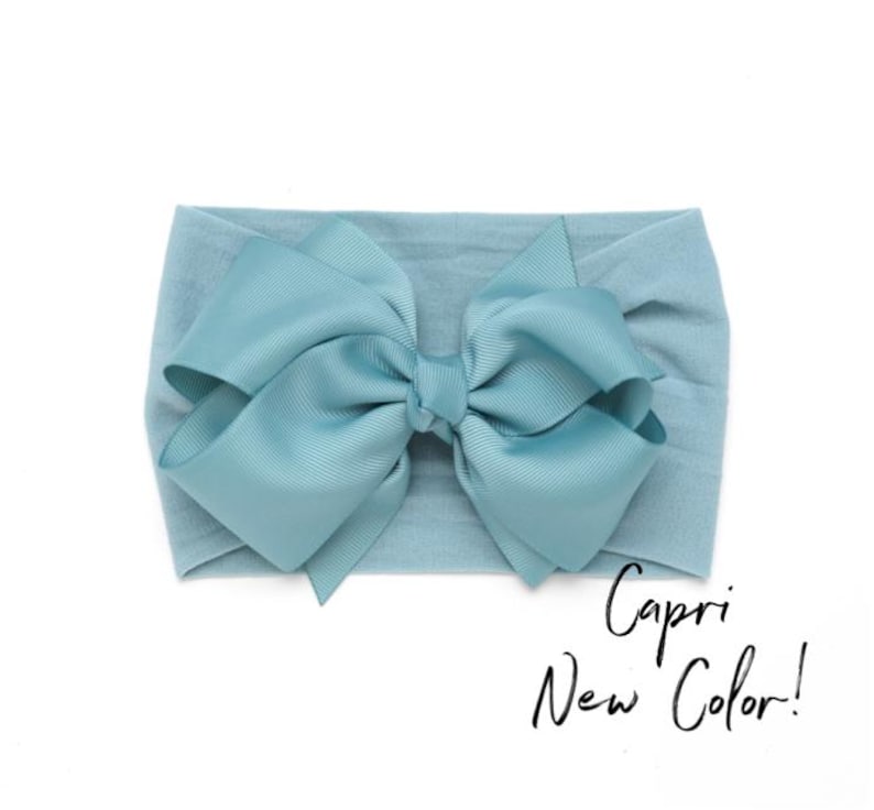Peut inclure: Un bandeau pour b&eacute;b&eacute; bleu clair avec un grand n&oelig;ud. Le bandeau est en tissu doux et extensible, et le n&oelig;ud est en satin assorti. Le texte sur l'image indique "Capri New Color!"