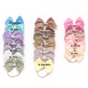 May include: A set of 20 hair bows in various colors, including vivid blue, aqua, lavender, purple grey, silver, white, sage, pecan, natural, fossil, latte, vanilla, carmandy, baby maize, bubblegum, rose, blush, peony pink, baby pink, and ivory. Each bow is tied with a matching elastic headband.