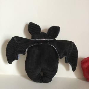 Puede incluir: Un peluche de murci&eacute;lago de pana negro con las alas extendidas. El murci&eacute;lago tiene orejas peque&ntilde;as y erguidas y un cuerpo redondeado. Las alas tienen un detalle de tela m&aacute;s clara en los bordes. El peluche est&aacute; dise&ntilde;ado para estar de pie.