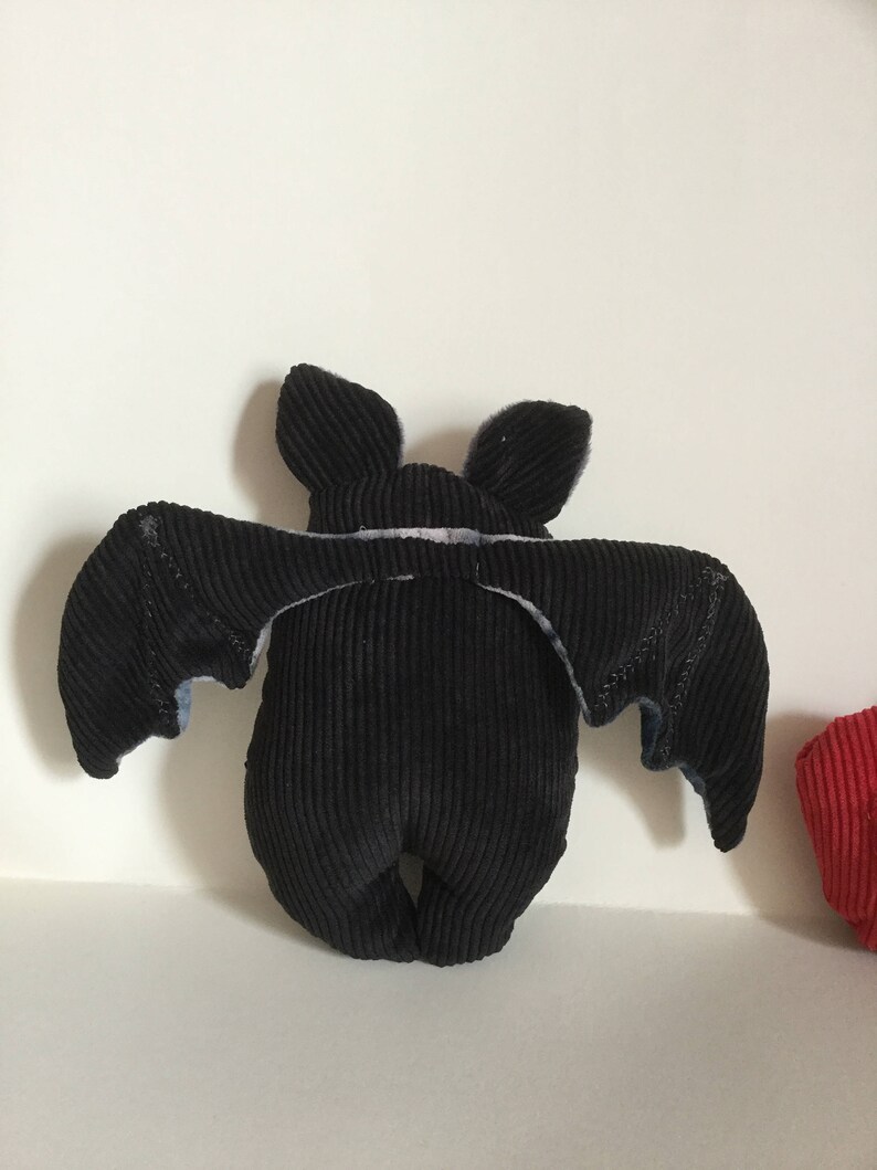 Puede incluir: Un peluche de murci&eacute;lago de pana negro con las alas extendidas. El murci&eacute;lago tiene orejas peque&ntilde;as y erguidas y un cuerpo redondeado. Las alas tienen un detalle de tela m&aacute;s clara en los bordes. El peluche est&aacute; dise&ntilde;ado para estar de pie.