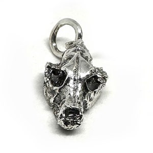 May include: A silver charm in the shape of an animal skull. The skull is detailed and realistic, with visible teeth and eye sockets.