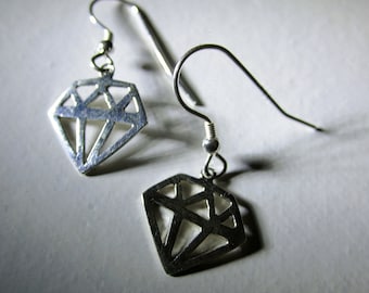 May include: A pair of silver earrings with a diamond shape design. The earrings are made of metal and have a simple, geometric design.