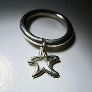 May include: A silver ring with a dangling silver starfish charm.