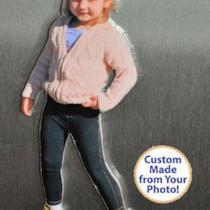 May include: A photo of a young girl wearing a pink sweater, black pants, and pink shoes. The image is a custom-made magnet from a photo. The text on the magnet reads "Custom Made from Your Photo!"