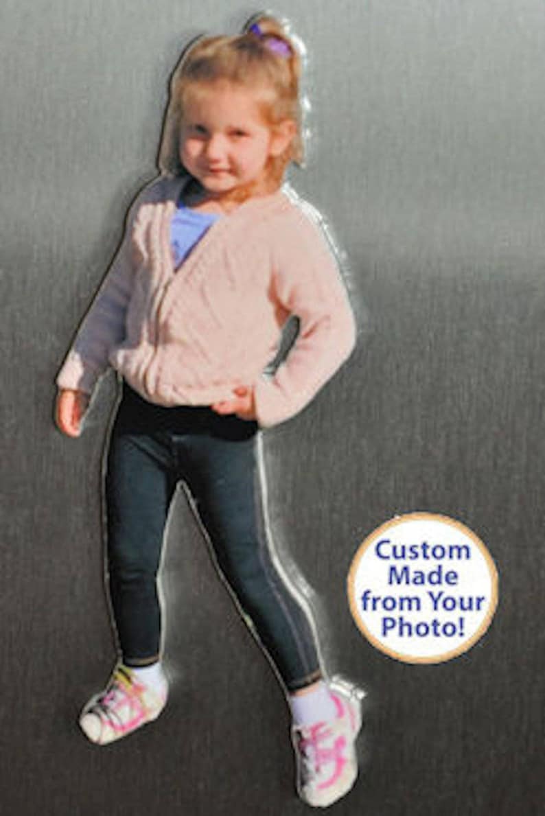 May include: A photo of a young girl wearing a pink sweater, black pants, and pink shoes. The image is a custom-made magnet from a photo. The text on the magnet reads "Custom Made from Your Photo!"