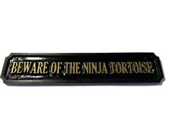 Rectangular Cuidado con la casa de la tortuga ninja o la placa de pared de la puerta negra con letras doradas en relieve