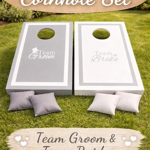 May include: A cornhole set featuring two rectangular wooden boards with circular holes. One board is grey with white trim and the text Team Groom, the other is white with grey trim and the text Team Bride. Four square bean bags are included.