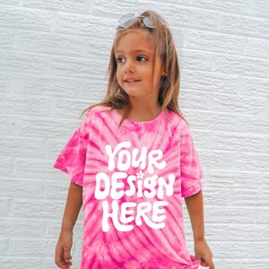 May include: A pink tie-dye t-shirt with the text "YOUR DESIGN HERE" in white. The shirt is made of a soft, comfortable material and is perfect for everyday wear.