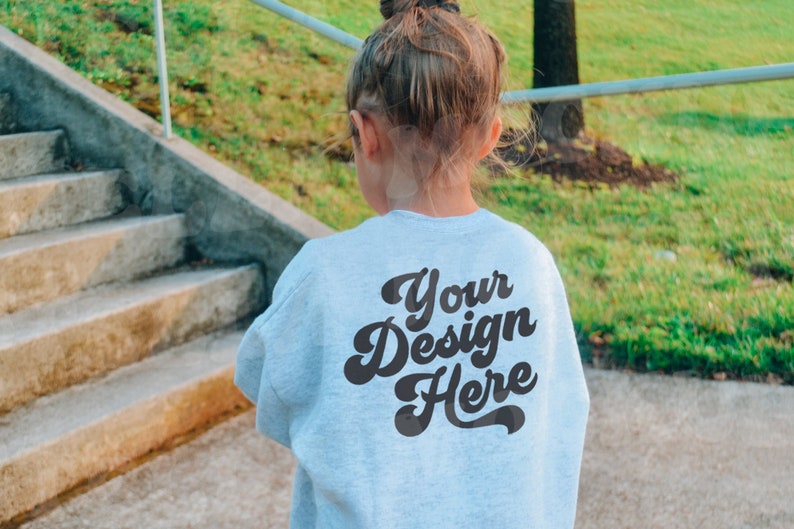 May include: A light blue sweatshirt with the text "Your Design Here" printed on the back in a retro font.