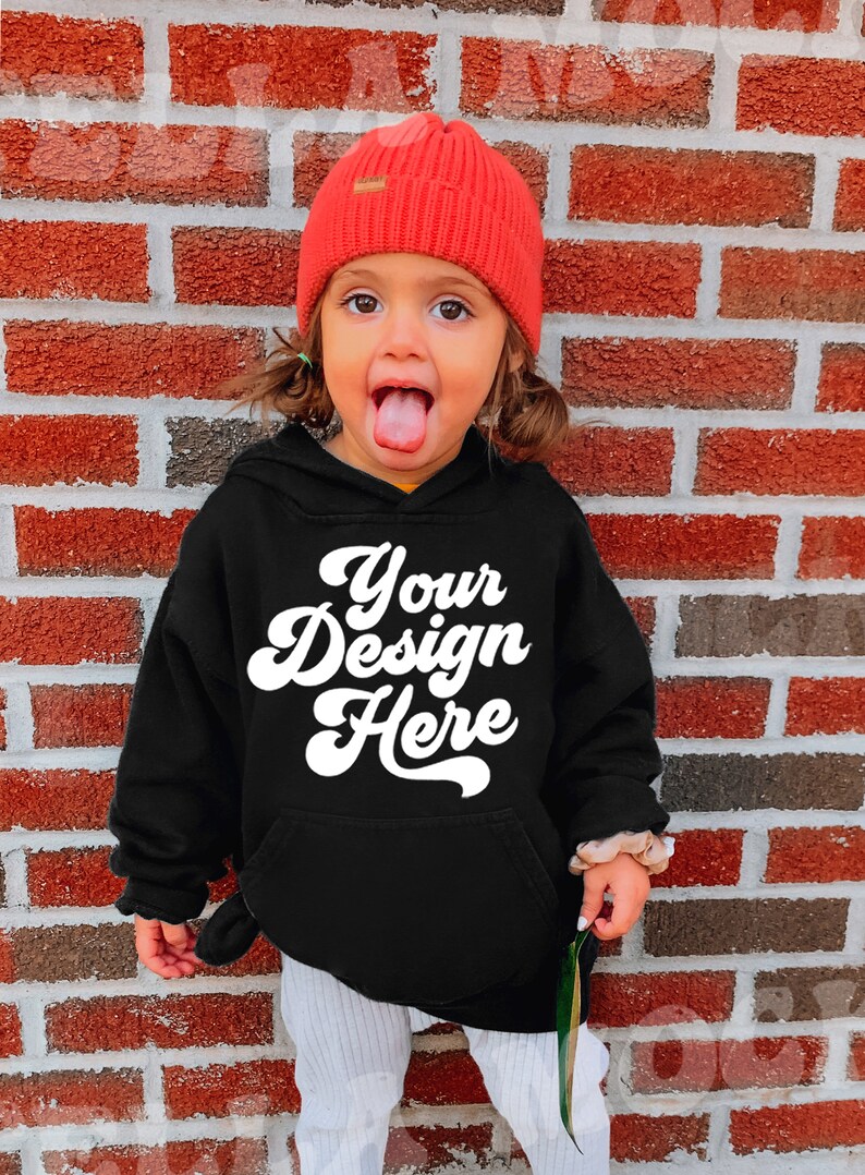 Może przedstawiać: Czarna bluza z kapturem z napisem "Your Design Here" w białym retro-foncie. Małe dziecko nosi bluzę i czerwoną czapkę.