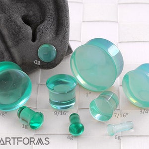 May include: Assortment of green and opal acrylic ear gauges in various sizes, including 7/8 inch, 1 inch, 3/4 inch, 9/16 inch, 7/16 inch, 1 gauge, 4 gauge, and 6 gauge.