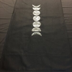 May include: Black fabric with a white design of the phases of the moon.