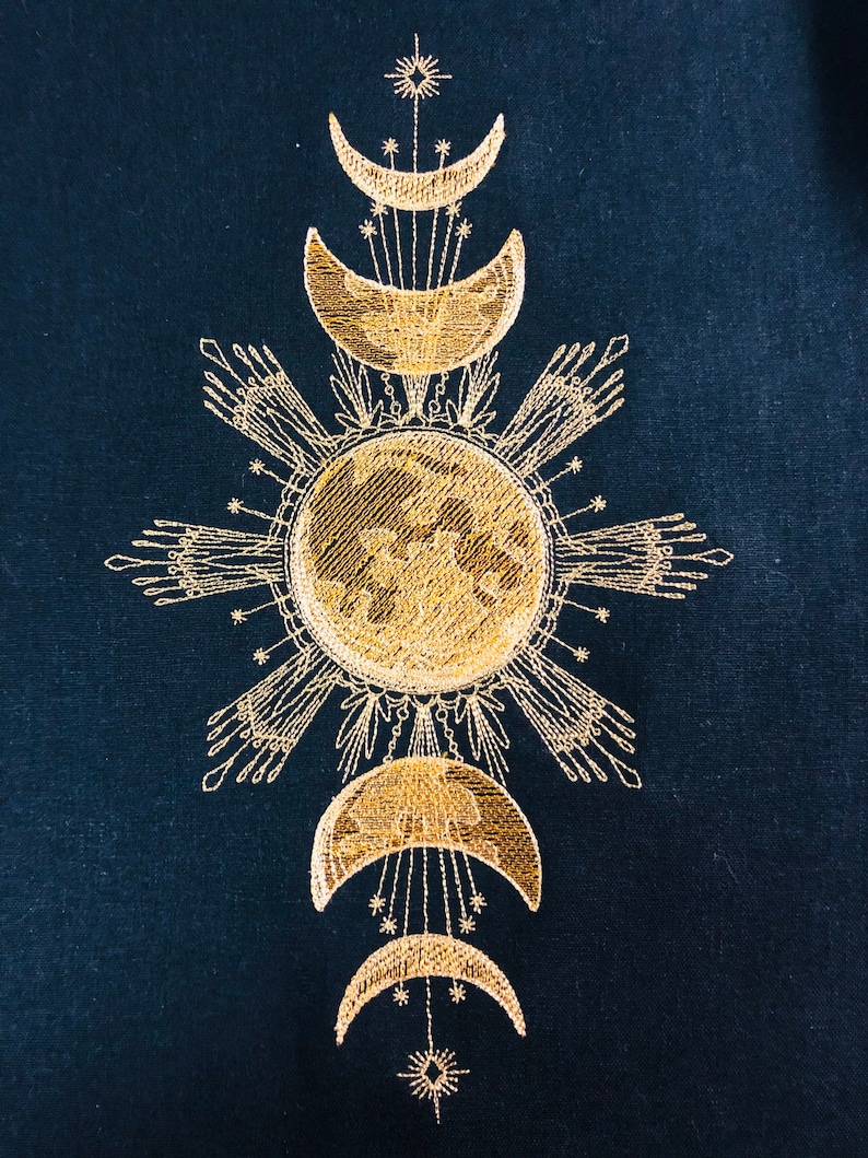 May include: Gold embroidered design on a dark blue fabric featuring a sun with rays and four crescent moons.